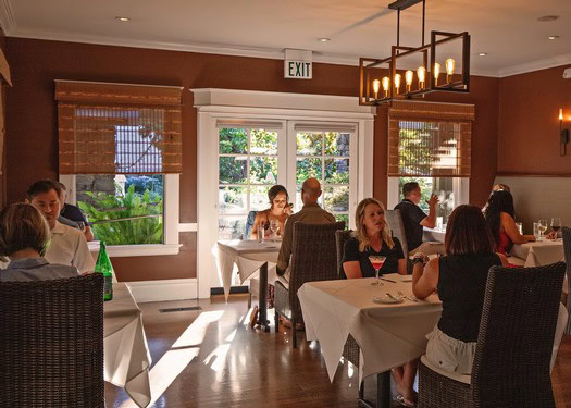 People dining at a restaurant with sunlight streaming through windows, showcasing Lodi wine region ambiance.