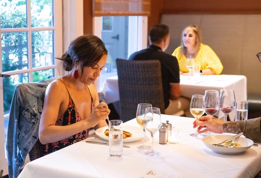 People enjoying wine and food at a restaurant, promoting Lodi winegrapes and local wine culture.