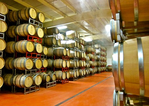 Wine barrels stored in a winery cellar, part of Lodi Winegrape Commission's wine production process.