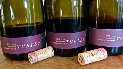 Three bottles of Lodi wine from Turley Winery with corks in front, showcasing vintage labels and wine varieties.