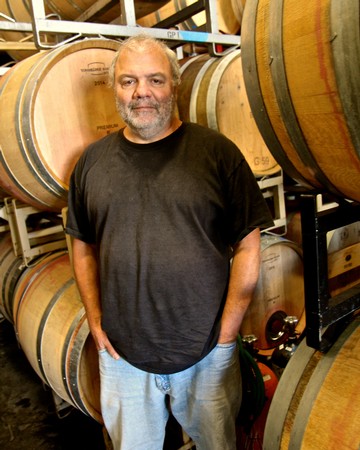Man standing in wine barrels at Lodi Winegrape Commission facility.