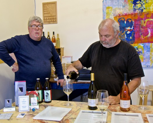 Two men tasting wine at a Lodi Winegrape Commission event with bottles and glasses on the table.