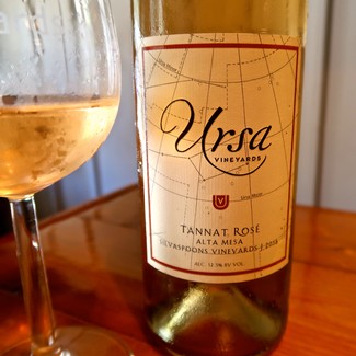 Bottle of Ursa Vineyards Tannat Rosé wine with a glass of rosé wine beside it.