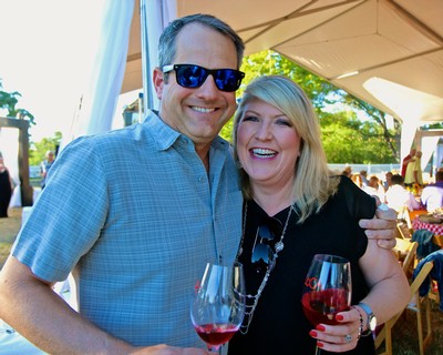 Smiling man and woman enjoying wine at Lodi Winegrape Commission event outdoors.