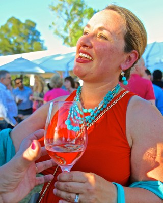 Woman enjoying wine at Lodi Winegrape Commission outdoor event with a glass of rosé wine.