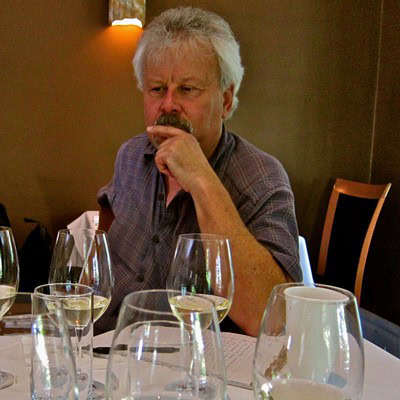 Man tasting wine at Lodi Winegrape Commission event, surrounded by wine glasses and a warm indoor setting.
