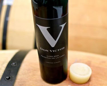 Bottle of Don Victor Lodi wine from Lodi Winegrape Commission with cork on wooden surface.