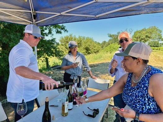 Group of people enjoying wine tasting outdoors at Lodi Winegrape Commission event.