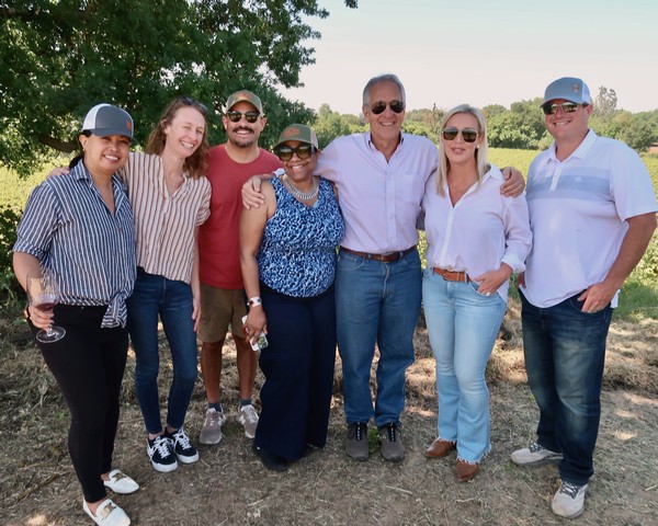 Group of people enjoying outdoor wine tasting at Lodi Winegrape Commission event.