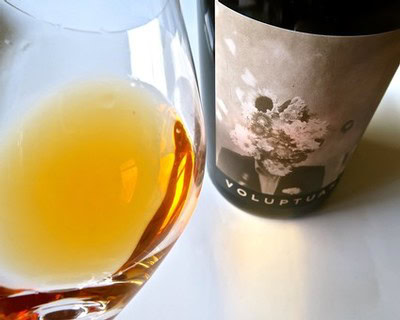 Close-up of a wine glass filled with golden wine and a wine bottle with a moonlit sky label from Lodi Winegrape Commission.
