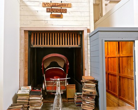 Vintage bicycle with stacks of wine-related books and a stroller in a cozy wine cellar setting.