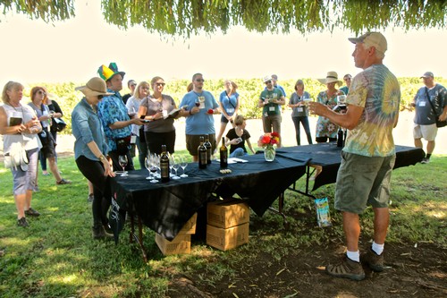 Group of people at an outdoor wine tasting event under a shaded canopy in Lodi, California.