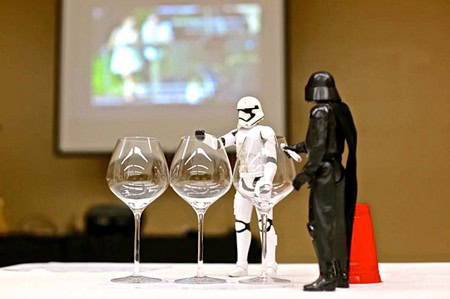Star Wars-themed figurines and wine glasses on a table, with a blurred background.