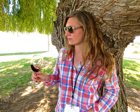Woman with sunglasses tasting red wine outdoors in Lodi wine country under a large tree.