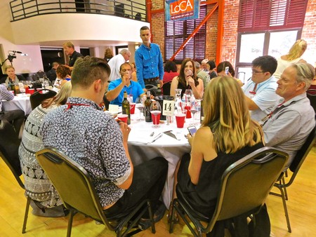 Group of people attending a Lodi Winegrape Commission event, seated around a table with wine bottles and glasses.