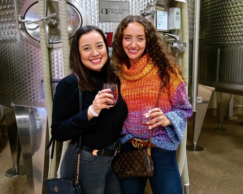 Two women enjoying wine at a Lodi Winegrape Commission event, smiling and holding glasses of red wine.