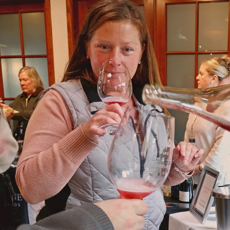 Woman tasting wine at Lodi Winegrape Commission event, wine glass in hand, in a warm, inviting setting.
