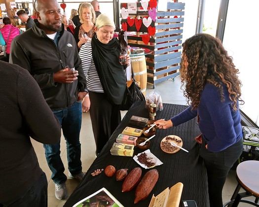 People tasting wine and local products at Lodi Winegrape Commission event in a bright indoor setting.