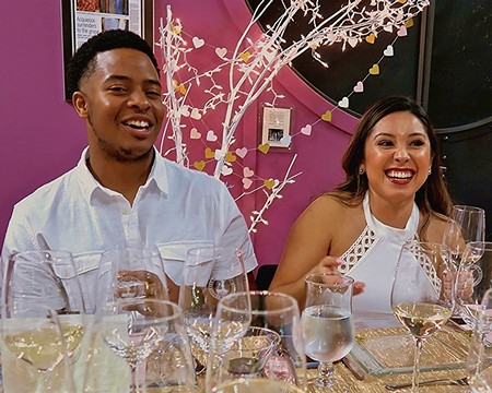 Two smiling people enjoying a wine tasting event with glasses of white wine at a Lodi Winegrape Commission gathering.