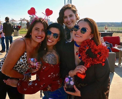 Group of women celebrating at Lodi Winegrape Commission event with festive accessories and wine glasses.