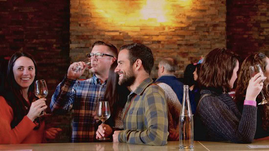 People enjoying wine tasting at a Lodi Winegrape Commission event in a cozy setting.