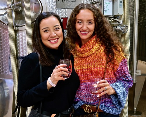 Two women enjoying wine at a Lodi Winegrape Commission event, smiling and holding glasses of red wine.