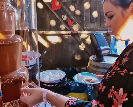 Woman serving chocolate at a Lodi Winegrape Commission event with festive decorations.