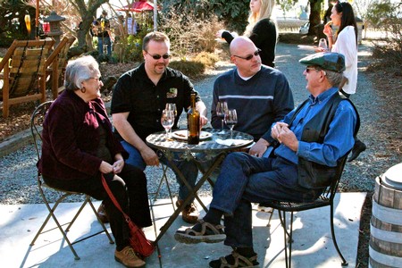 Group of four people enjoying wine outdoors at a vineyard event in Lodi, California.