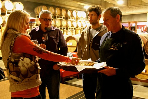 Group of people tasting wine at Lodi Winegrape Commission event in a winery cellar.