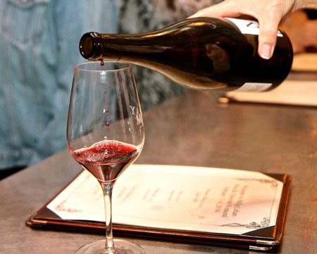 Pouring red wine into a glass at a wine tasting event, showcasing Lodi's wine industry.