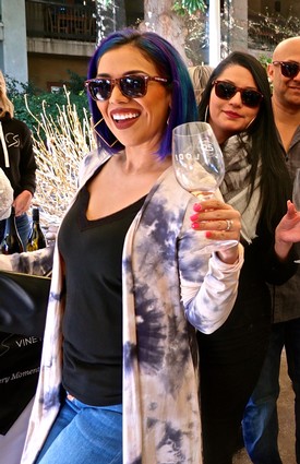 Woman with colorful hair holding a wine glass at Lodi Winegrape Commission event.