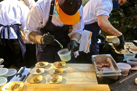 Chef preparing gourmet dishes at Lodi Winegrape Commission event with multiple plates and ingredients.