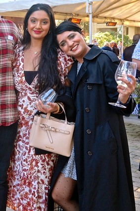 Two women smiling and holding wine glasses at a Lodi wine event, showcasing local wine culture and community.