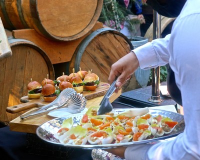 Chef serving a colorful pasta dish at a Lodi wine event with wine barrels in the background.