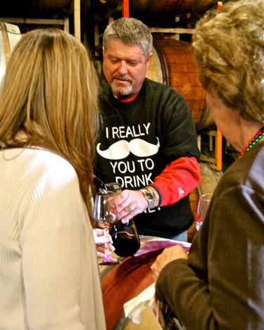 People tasting wine at a Lodi Winegrape Commission event in a winery setting.