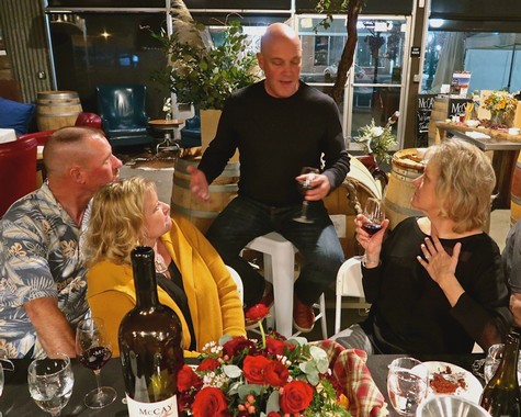Group enjoying wine tasting at a Lodi Winegrape Commission event with wine glasses and floral centerpiece.