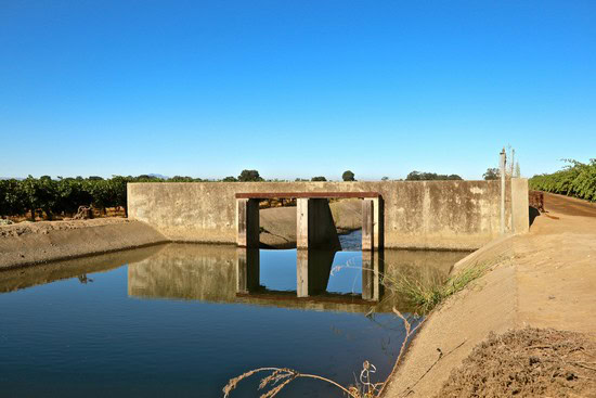 Waterway and concrete structure in Lodi wine region for irrigation and vineyard management.