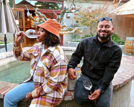 Two people enjoying wine tasting outdoors at Lodi Winegrape Commission event.