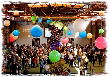 Crowd at Lodi Winegrape Commission event with colorful balloons and grapevine decorations.