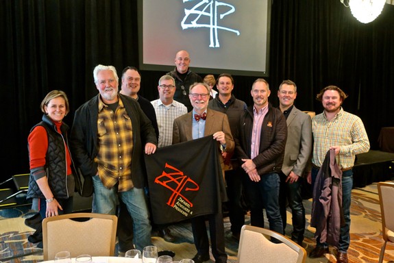 Group photo of Lodi Winegrape Commission members at an event, holding a banner with the organization's logo.