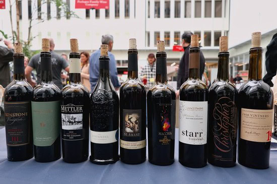 Collection of wine bottles from Lodi Winegrape Commission showcasing local wines at an outdoor event.
