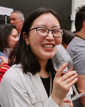 Smiling woman with glasses enjoying wine at Lodi Winegrape Commission event.
