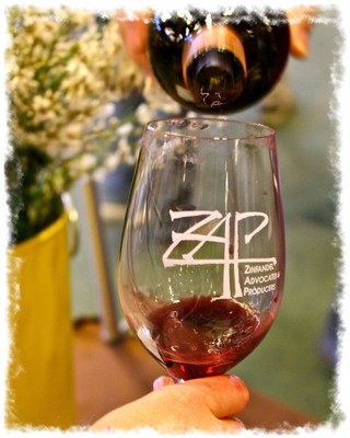 Person pouring red wine into a glass with Lodi Winegrape Commission logo, showcasing local wine production.