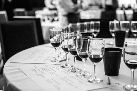 Multiple wine glasses filled with red wine on a table at a wine tasting event in Lodi, California.