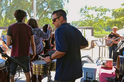 Musicians performing at a Lodi Winegrape Commission event outdoors with audience and trees in background.