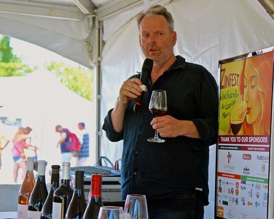 Man speaking at Lodi Winegrape Commission event holding a wine glass and microphone.