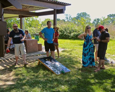 Group of people at Lodi Winegrape Commission event outdoors with wine tasting and scenic vineyard background.