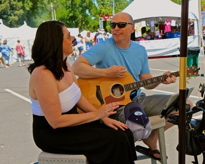 Man playing guitar and woman enjoying music at Lodi Winegrape Festival.