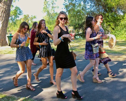 Group of women walking outdoors, enjoying a sunny day at a wine event in Lodi, California.