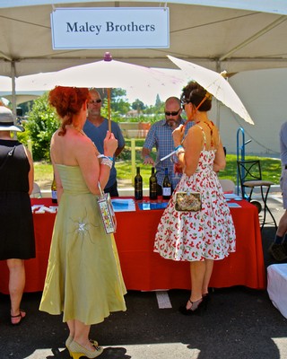 People tasting wine at Lodi Winegrape Commission booth during outdoor event.
